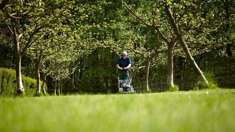 Gardener mowing grass at Rufford Old Hall, Lancashire
